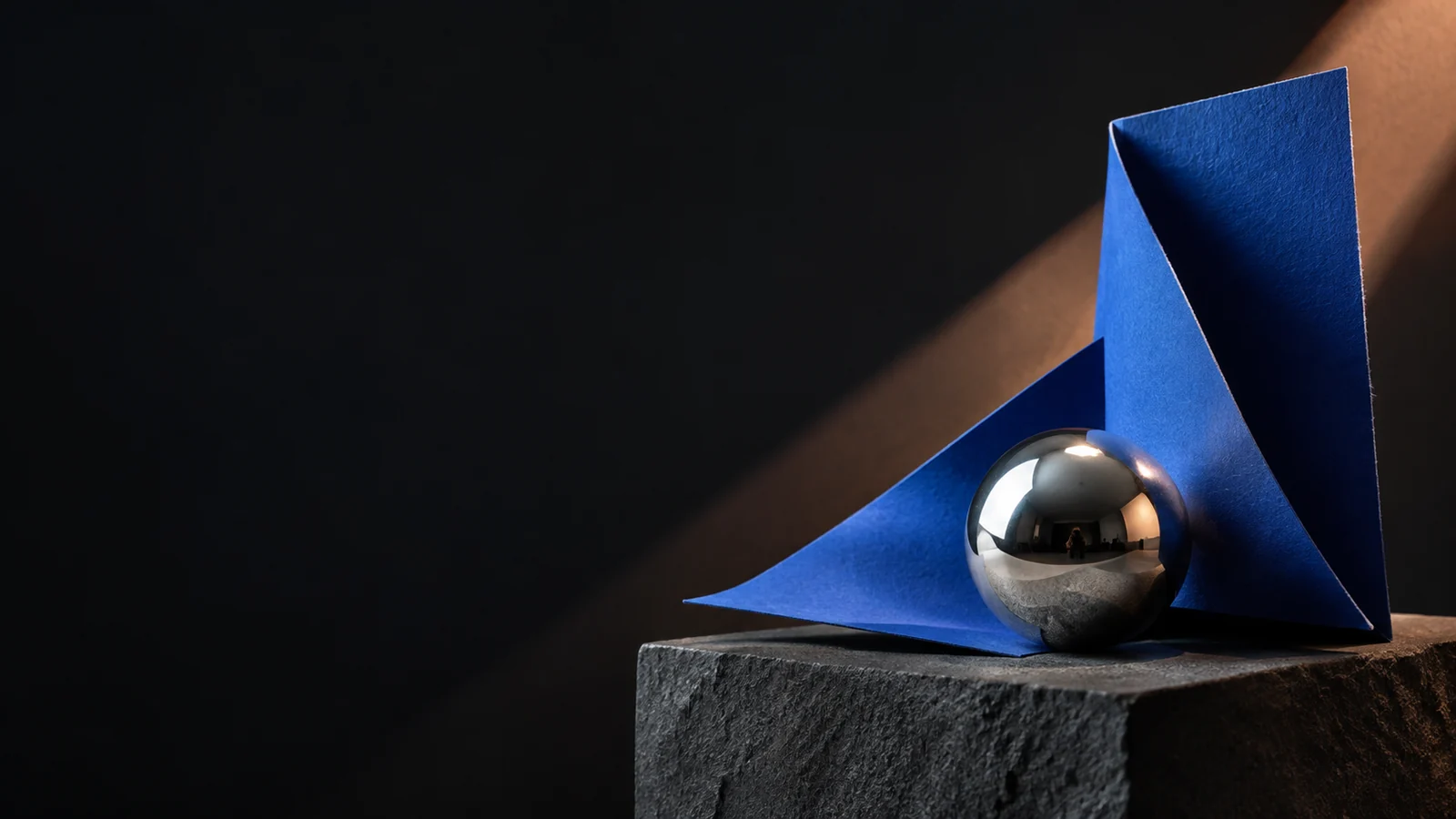 Sculptural cobalt paper and silver sphere in a studio composition
